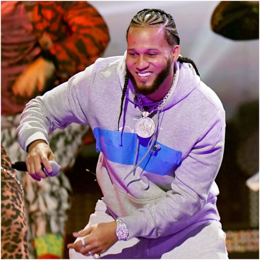 El Alfa holding a microphone while performing on stage