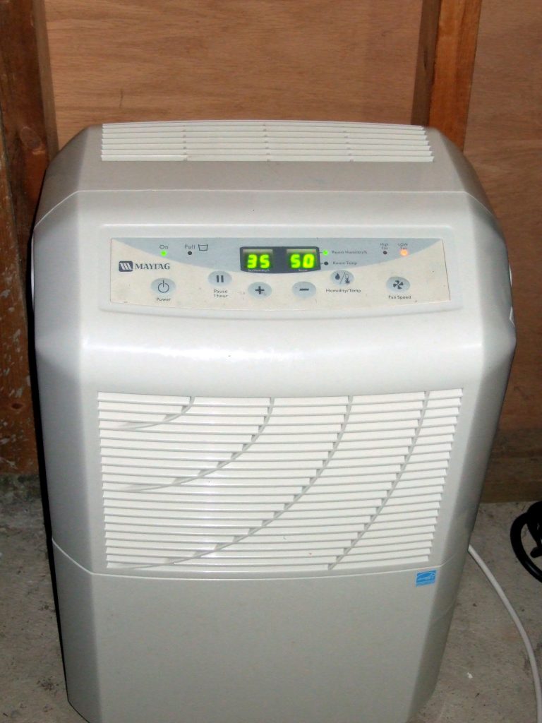 a white dehumidifier kept on the ground