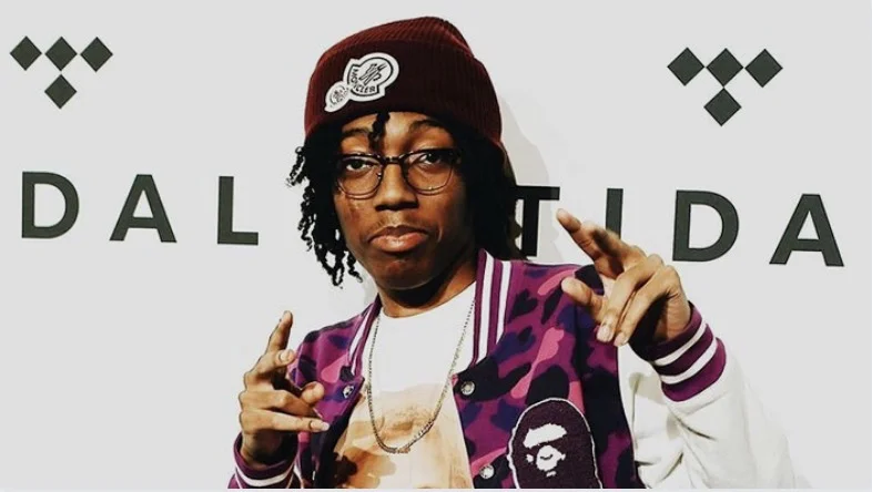 Lil Tecca on a purple jacket with his hands up