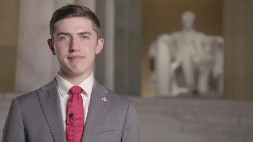 Nick Sandmann putting on a a suit and a red tie