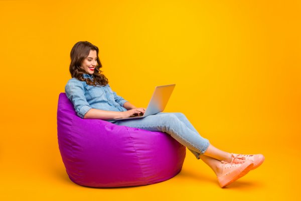 a lady sitting on a purple bean bag with a laptop on her laps