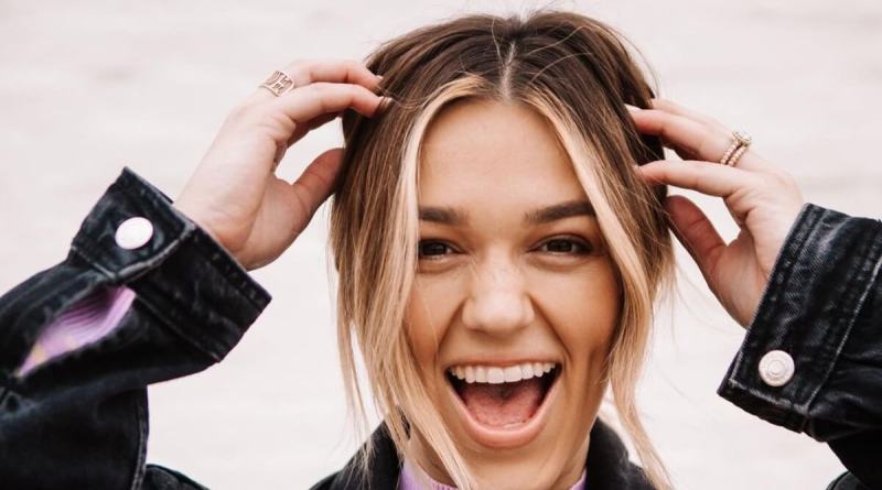 Sadie Robertson smiling while touching her hair