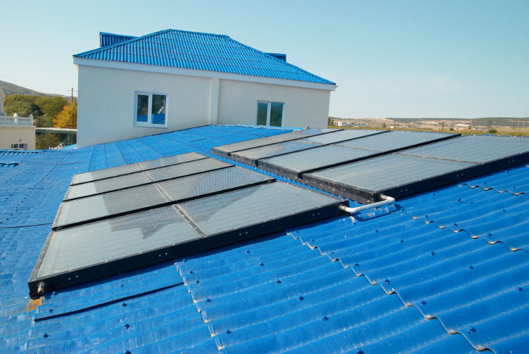 a solar flat plate collector fixed on a blue colored roof of a building