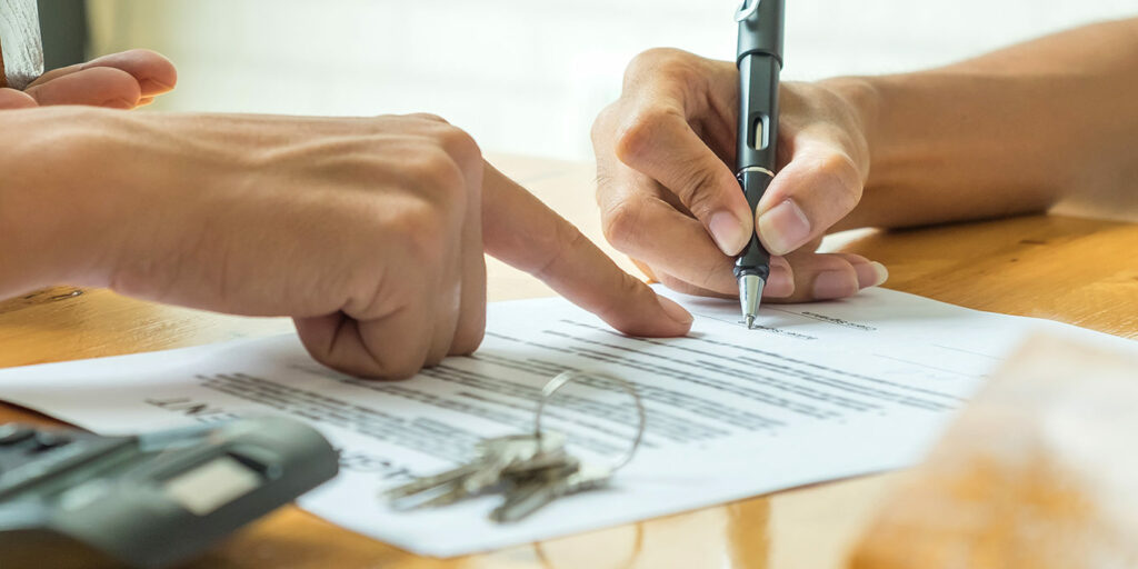 hands on the table while writing on a paper 