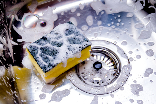 A sponge being used in cleaning the sink
